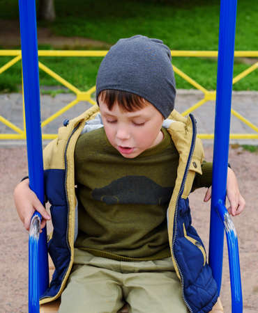 Cute adorable toddler girl swinging on outdoor playground. Happy smiling baby child sitting in chain swingの写真素材