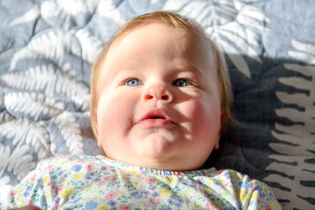 Cute girl of ten months old, playing alone in a crib at home in the afternoon or in the morning.