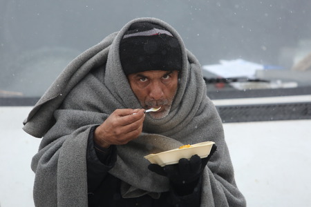 Belgrade, Serbia - January 17, 2017: Migrant eat outdoors even though it's cold. Migrant have occupied an abandoned customs warehouse in Belgrade as they seek ways to move to EU.のeditorial素材