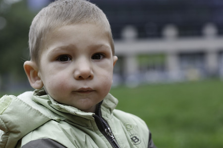 Close up exterior portrait of boy wearing autumn jacket in park.の写真素材