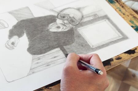 artist drawing a pencil illustration for the second edition of his illustrated children's book, which is on the glass table. Creative environmentの写真素材