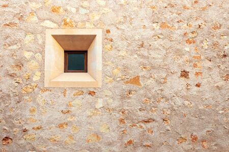 Stone facade with square window of popular architecture of the island of Majorca, Spain. Background image and stone textureの写真素材