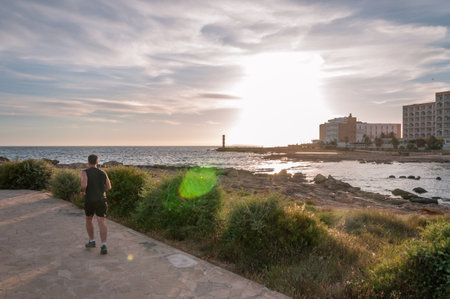 Colonia de Sant Jordi, Balearic Islands/Spain; june 2020: runner on the Colonia de Sant Jordi promenade at sunset. Island of Mallorca, Spainのeditorial素材