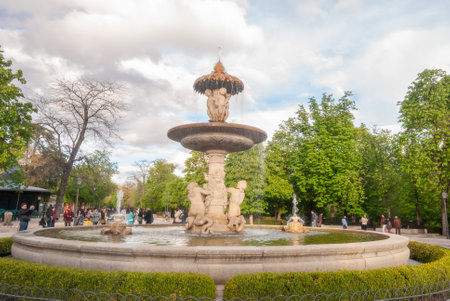 Madrid, Spain; April 2010: Neoclassical sculpture fountain in the gardens of the Parque del Buen Retiro, a sunday with pedestriansのeditorial素材