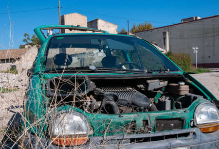 Abandoned green car and scrapped in an abandoned lot. Vandalism imageの写真素材