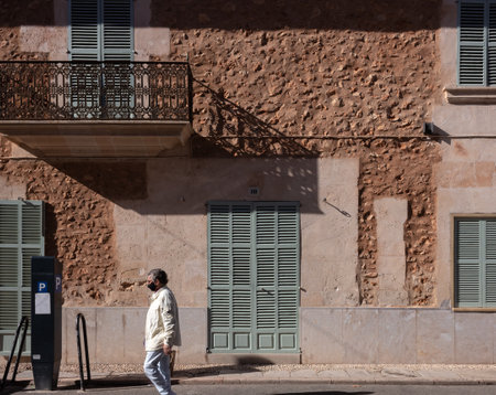 Campos, Balearic Islands / Spain; October 2020: older man walking down a sunny street wearing a face mask because of the Coronavirus pandemic. New normal conceptのeditorial素材