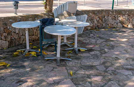 White plastic chairs stacked next to outdoor tables. Restaurant businesses closed by Coronavirus