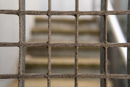 Deteriored iron fence. At the background of the image an unfocused staircase. Urban imageの写真素材