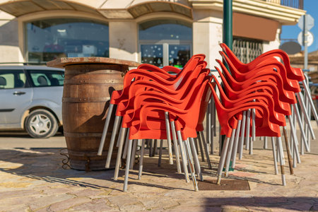 Red plastic chairs stacked outside a cafeteria closed by the virus crisis. Background of the image out of focus. Restrictions in the restorationの写真素材