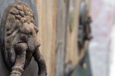 Close-up of a metal knob in the shape of a lion's head, made of rusty iron. The background of the image is blurried with the bokeh effectの写真素材