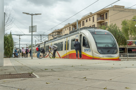 Manacor, Spain; March 18 2021: Passengers waiting to board the train on the track platform with face...