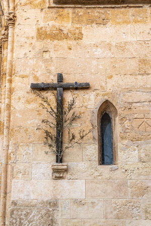 Wooden cross with olive branch next to a Gothic window on the main facade of the Christian church of Sineu, Mallorca island, Spainの写真素材