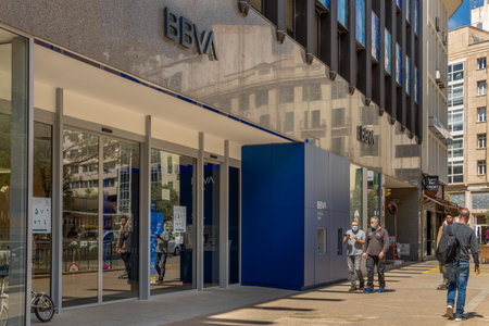 Palma de Mallorca, Spain; April 13 2021: Main facade of the Spanish bank BBVA, in the historic center of Palma, with people walking with masks due to the Coronavirus pandemic. New normalのeditorial素材