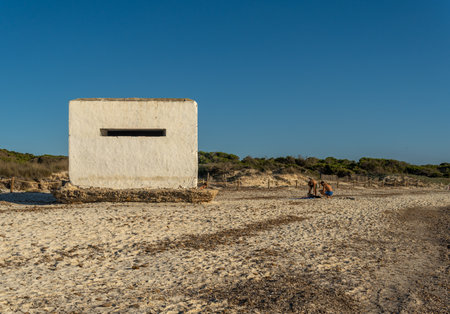 Es Trenc, Spain; October 11 2021: Old bunker of the Spanish civil war on the beach of Es Trenc, next to bathers, at sunset. Island of Mallorca, Spainのeditorial素材