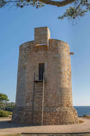 General view of the medieval tower Torre Nova in the Mallorcan tourist resort of Cala Santanyi, on a sunny day with the Mediterranean Sea in the backgroundの写真素材