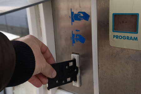 Close-up of a caucasian hand inserting a black card, in a car wash machine