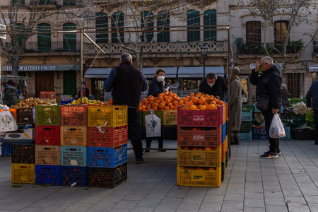 Llucmajor, Spain; january 07 2022: Weekly street market in the Majorcan town of Llucmajor. Vendors and customers with masks due to restrictions by the Omicron variant of Coronavirus. New normalのeditorial素材