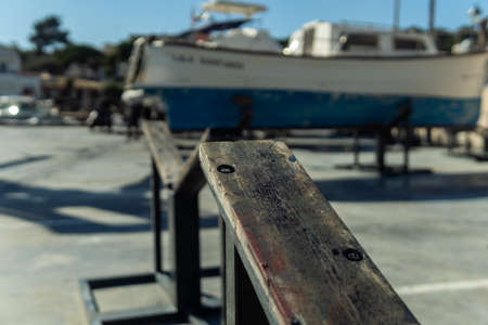 Close-up of wooden tripods to support a boat for future restoration. In the background, the marina of Portopetro out of focusの写真素材