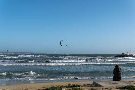People with their backs unrecognizable, looking at the windy sea of Playa de Palma de Mallorca,...
