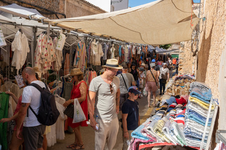 SantanyÃ­, Spain; july 09 2022: Weekly street market in the Majorcan town of Santanyi, Spain. Stalls selling clothes and fashion with tourists strolling aroundのeditorial素材