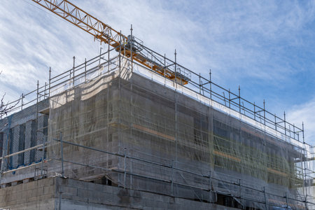 New building under construction with a yellow metal crane in the background. Island of Majorca,...