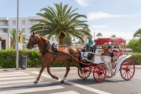 Sa Coma, Spain; June 03 2023: Horse-drawn carriage with tourists taking a ride in the Mallorcan tourist resort of Sa Coma, Spainのeditorial素材