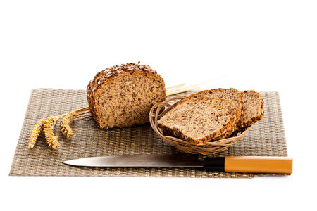 Loaf of wholemeal bread  cutting into slices on wood bread board with knife, isolated on white 