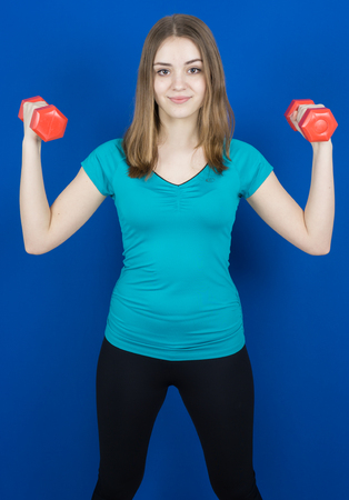 girl with dumpbells on blue background sport concept gymの写真素材