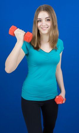 girl with dumpbells on blue background sport concept gymの写真素材