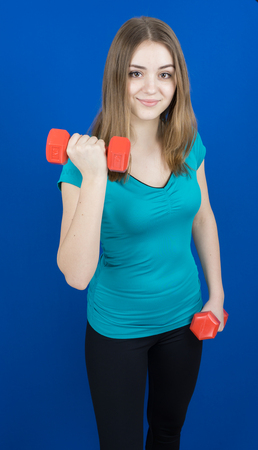 girl with dumpbells on blue background sport concept gymの写真素材