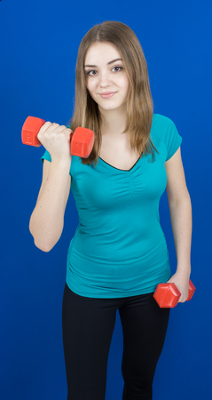 girl with dumpbells on blue background sport concept gymの写真素材