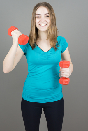 girl with dumpbells on grey background sport concept gymの写真素材