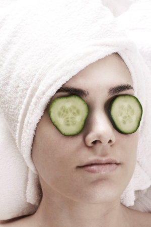 Portrait of young woman recieving a treatment in face with cucumber.の写真素材