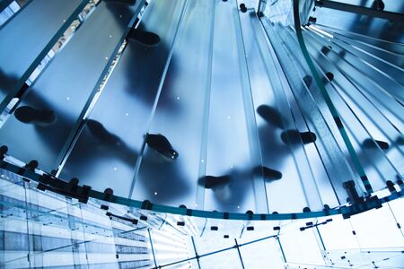 Modern glass staircase with people on top of it.の写真素材