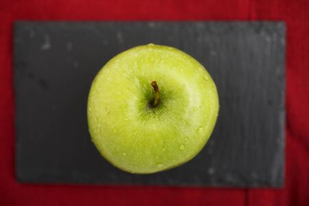 Green apple on blackboard on top of red napkin.の写真素材