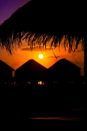 Colorful Sunset in Maldives with a silhouette of parasol and bungalows.の写真素材