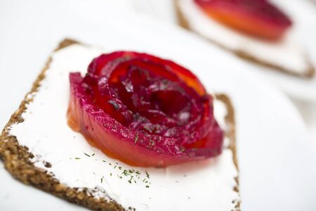Appetizer of marinated salmon over a black bread with dill dyed with beetroot.の写真素材