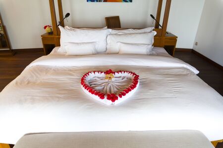 Towel forms a beautiful heart decorated with red flowers in a Luxury Resort room in Maldives.の写真素材
