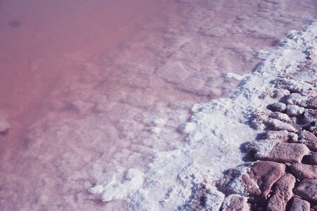 Textured of different shapes of rocks of salt in a pink water basin.の写真素材