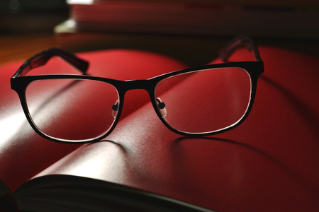 black glasses and red book with pagesの写真素材