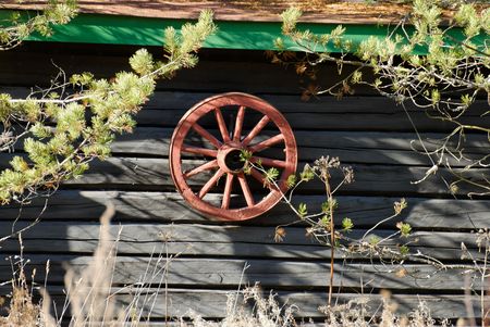 Red cartwheel hanging on a old house wall  の写真素材