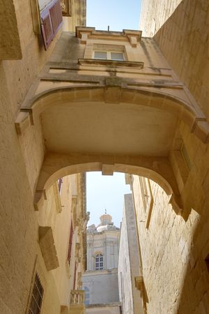 An arched bridge connecting two sandstone houses in Mdina, Malta. The image is HDR tonemapped from three individual exposures to enhance details.  の写真素材