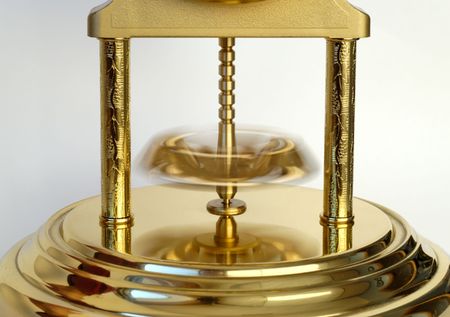 Rotating pendulum of a golden-coloured clock. の写真素材