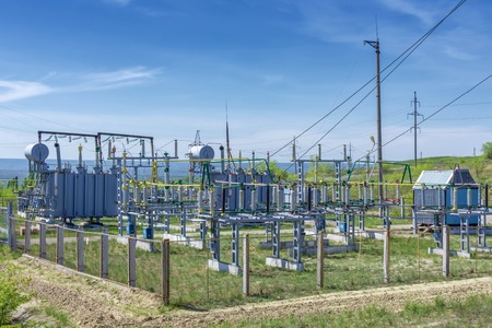 electrical distribution transformer substation, against the background of green vegetation, the sky...