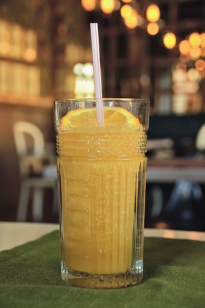 tall glass with orange juice, with a tube for cocktails, decorated with a slice of orangeの写真素材