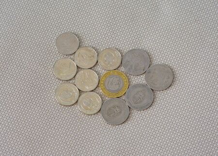 Tunisia bimetallic denominated half dinar, one and five dinar on an isolated white fabric background