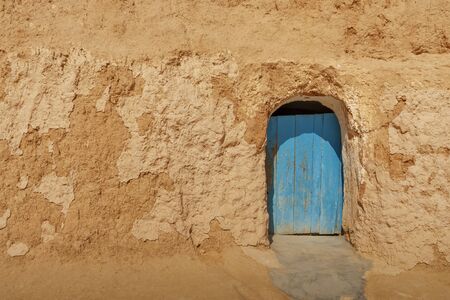 old wooden door painted with blue paint at the entrance to the cave, in the rock of red sandstoneの写真素材