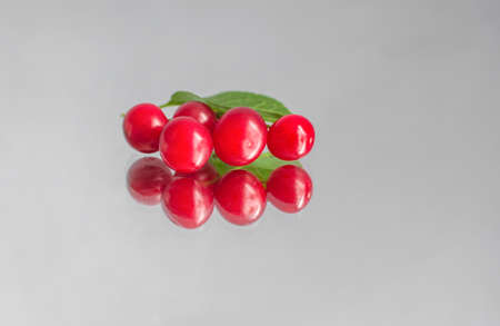 berries of ripe cherries and their reflection on a mirror surface, on an isolated backgroundの写真素材
