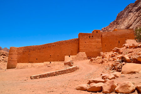 view from the side to the monastery of St. Catherine, against the backdrop of the mountains and the blue sky, the rare green desert vegetation, South Sinai, Egyptの写真素材