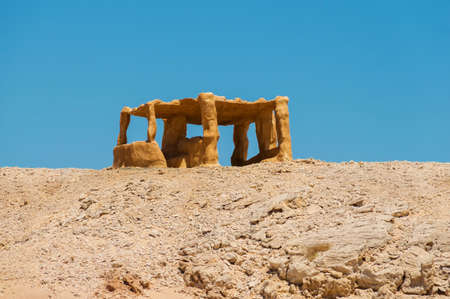 a lonely standing yellow stone arbor, standing alone in the desert on a hillの写真素材